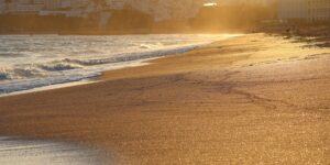 A serene, empty beach during golden hour representing off-peak travel opportunities.