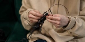 A close-up of hands mending a wool sweater, representing the slow fashion movement.