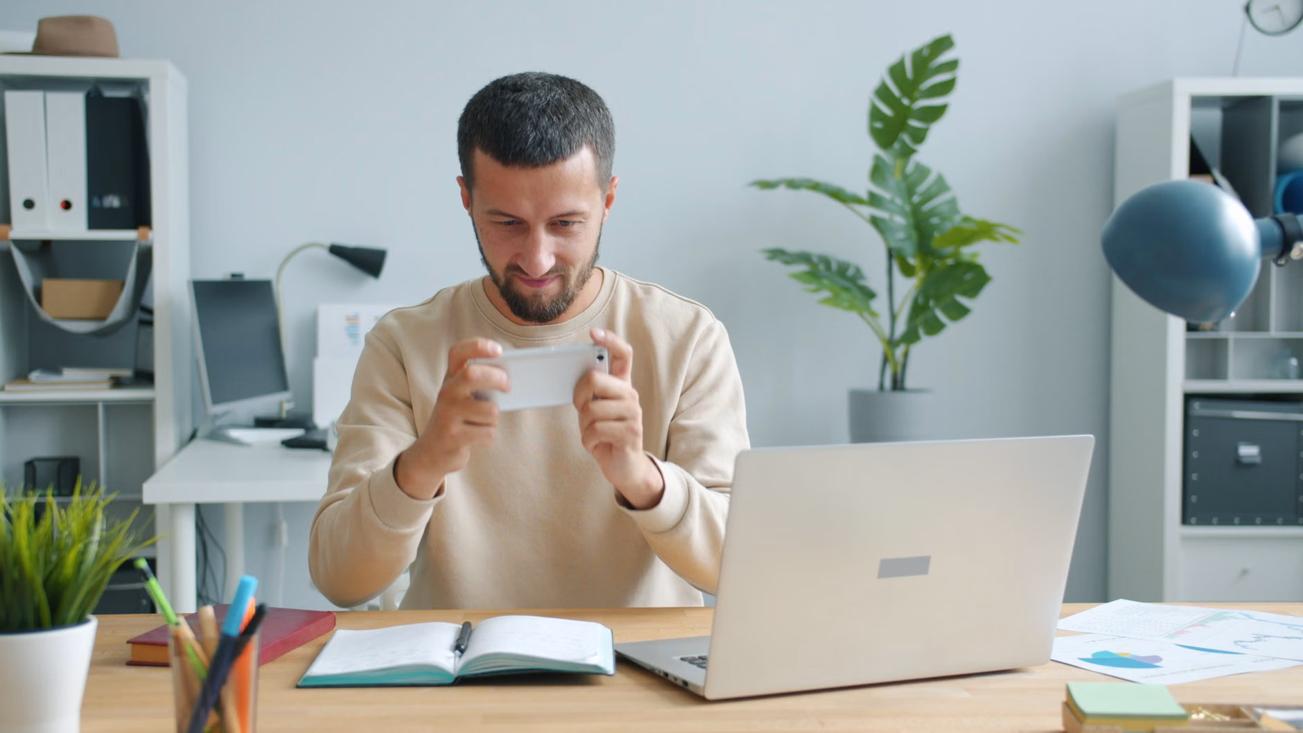 Person organizing digital life using a notebook and smartphone.