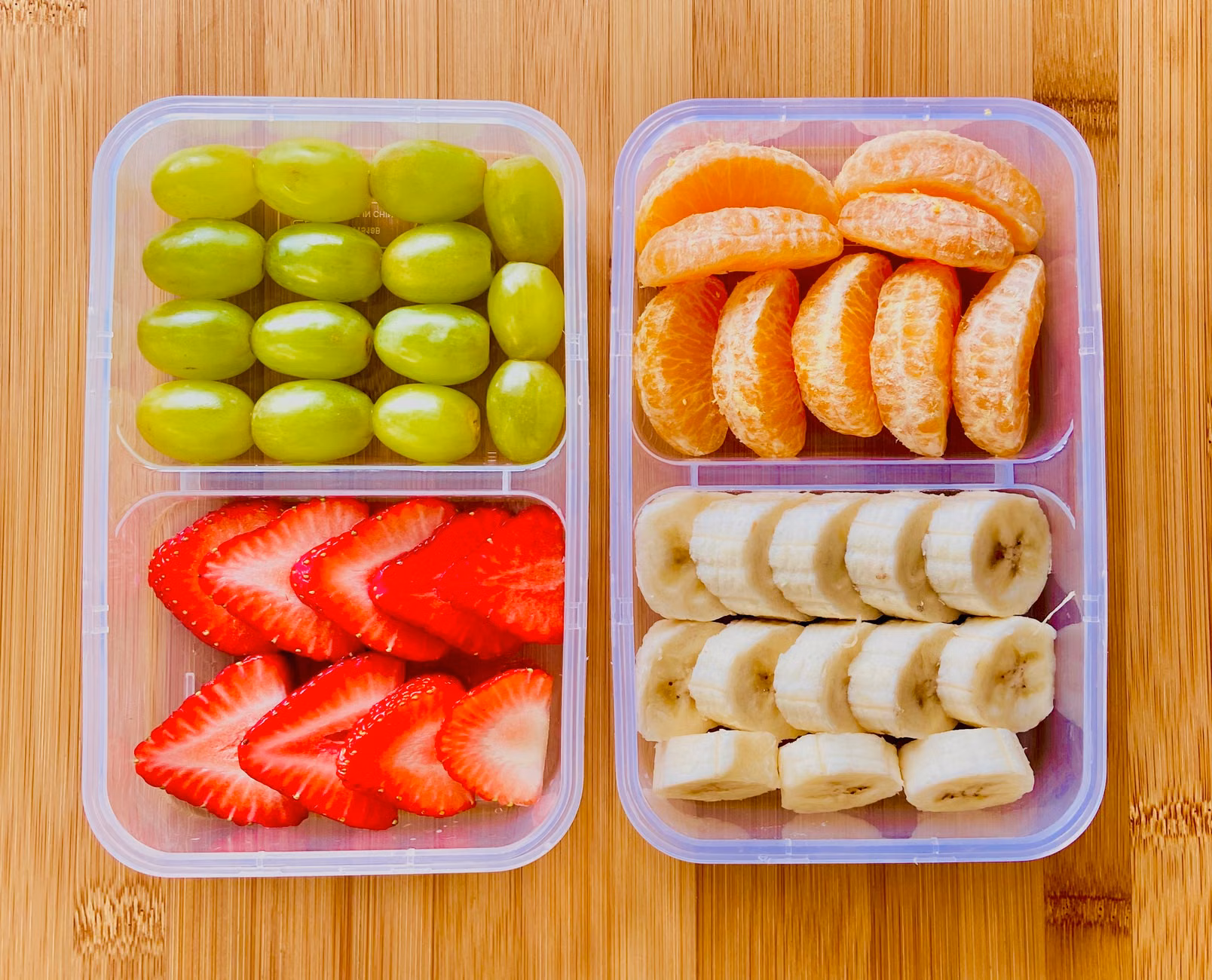 Segmented lunchbox container being filled with organized food groups.