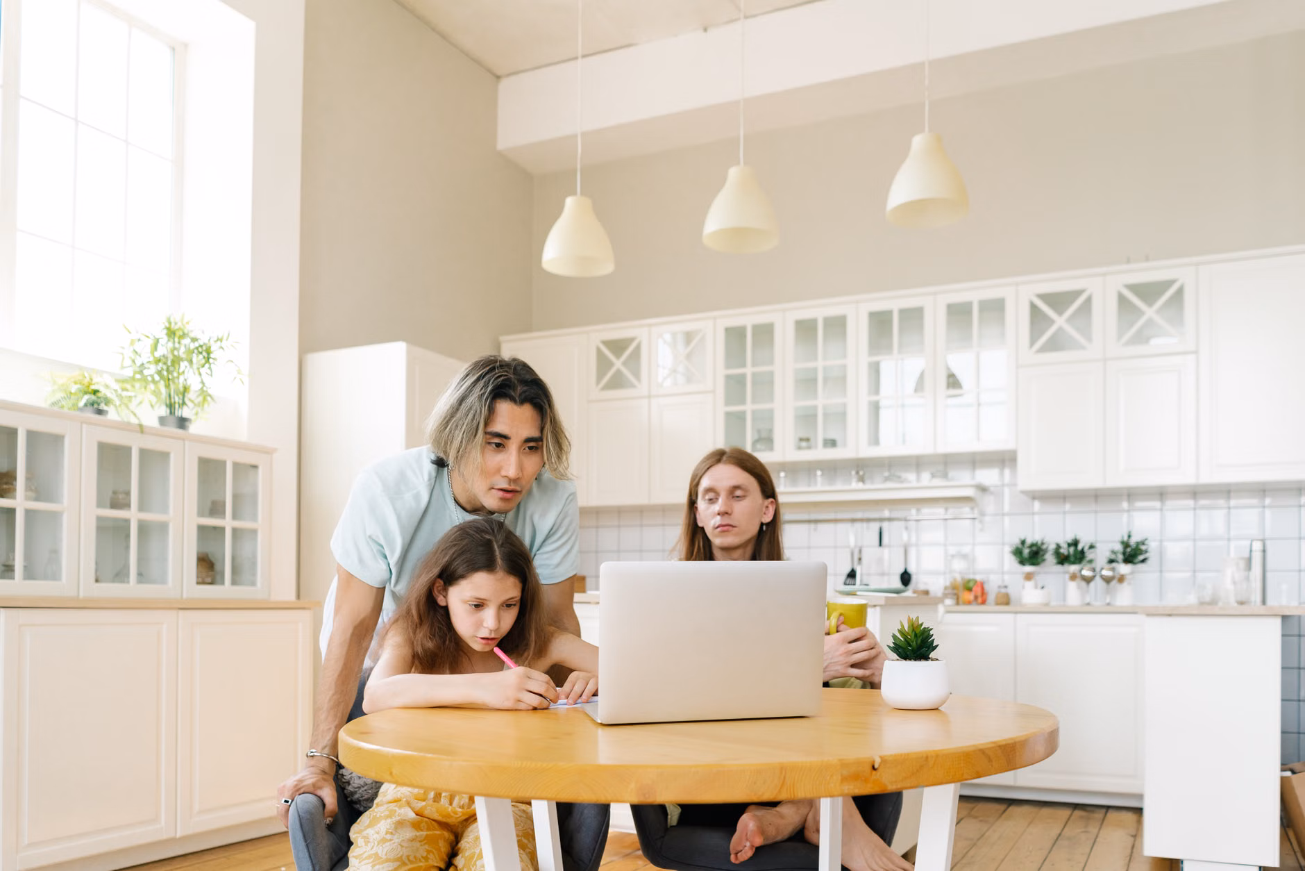 A parent organizing digital information at a kitchen table.