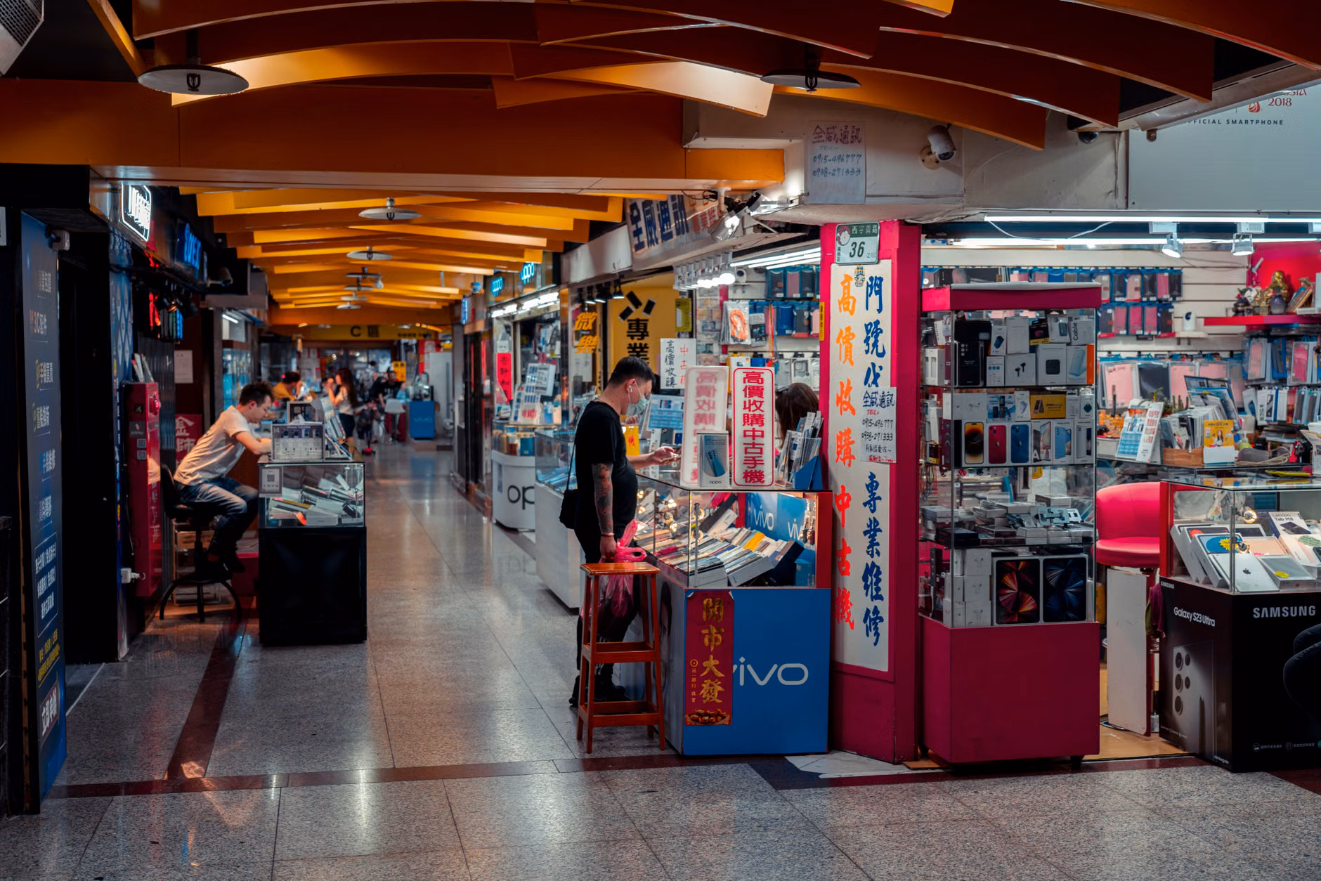 A shopper comparing electronics prices in a retail environment.