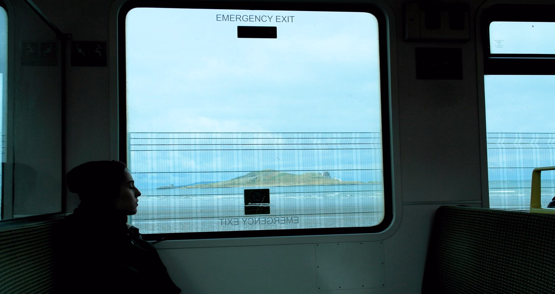 A family enjoying the view from a spacious coastal train carriage.