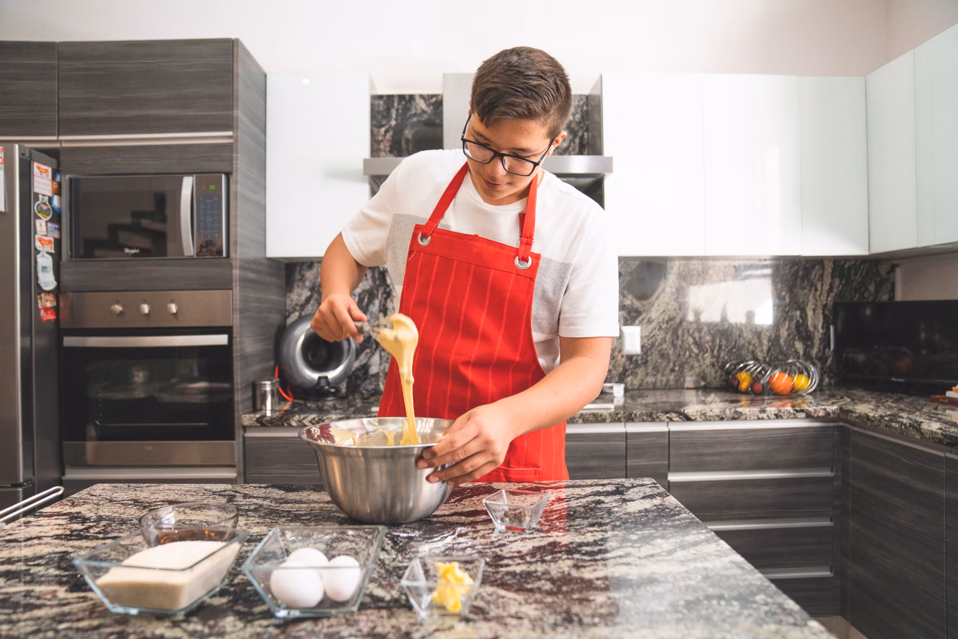 A pre-teen organizing ingredients for a cooking project using a checklist.