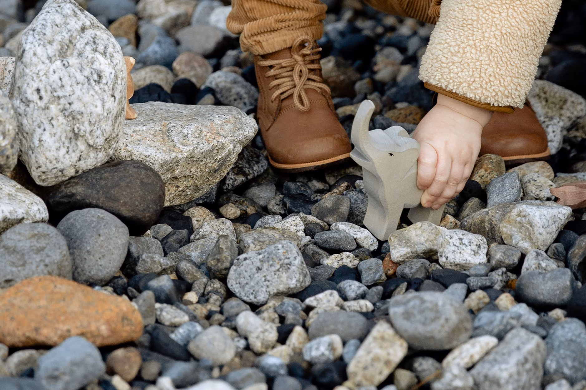 Toddler hands interacting with natural elements like bark and stones.