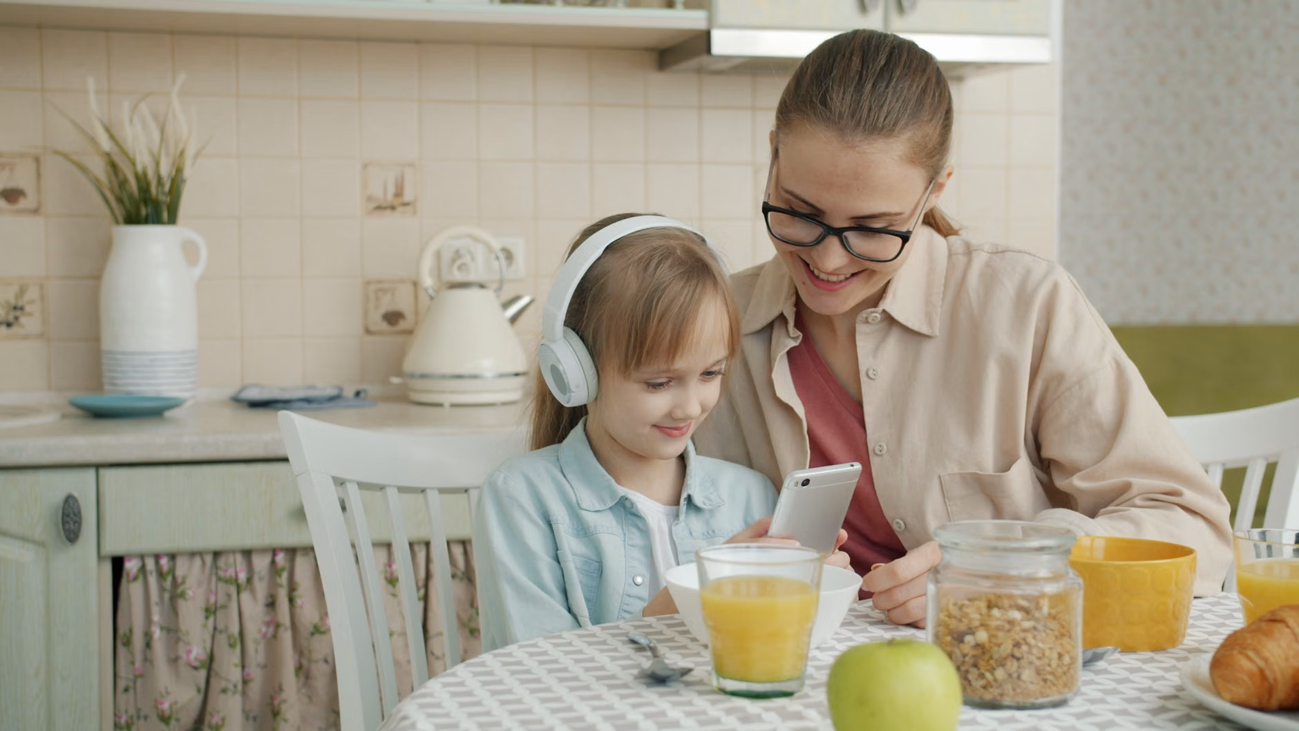 Parent adjusting privacy settings on a tablet at a kitchen table.