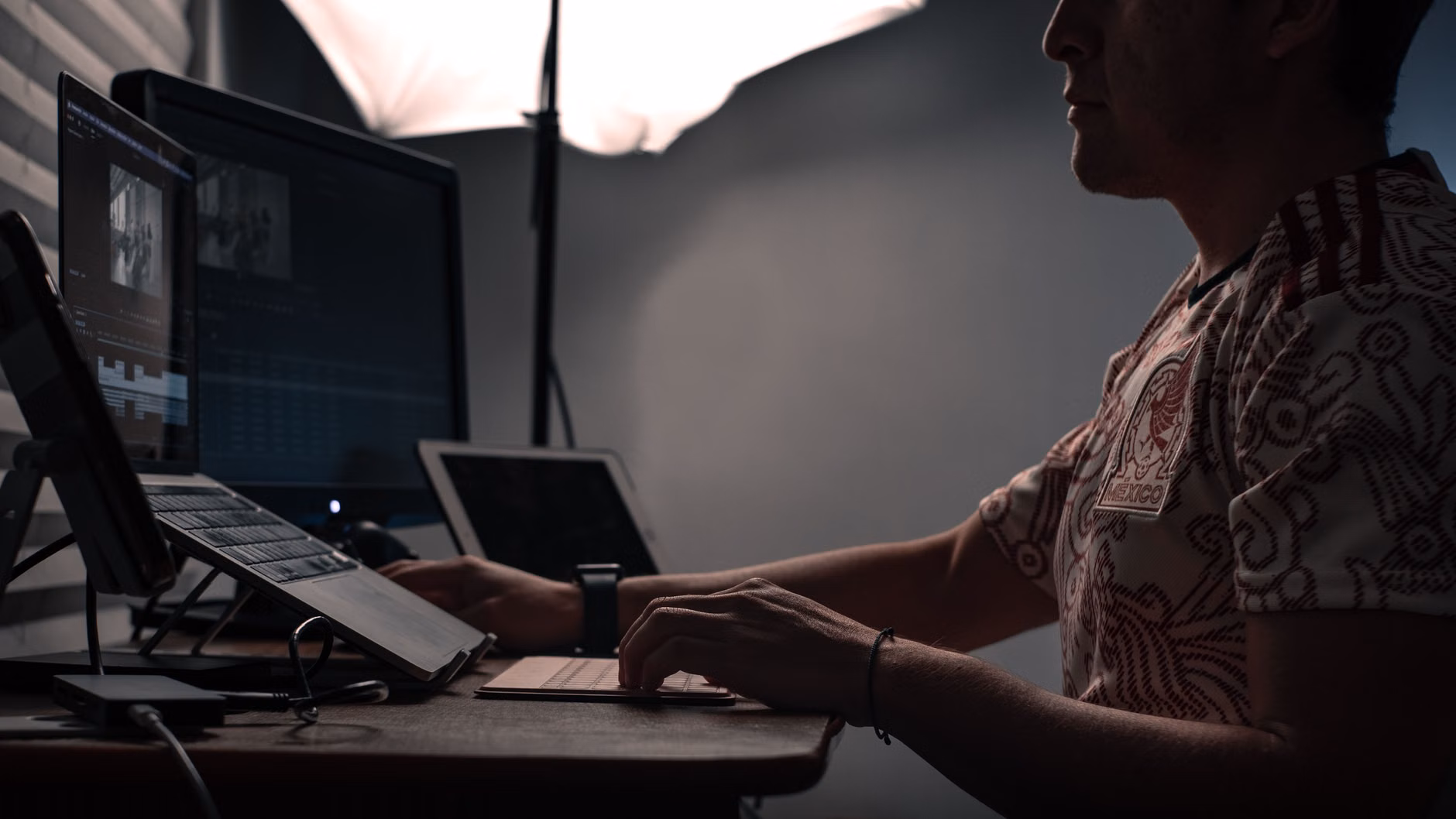 A teenager working on a creative project using multiple monitors.