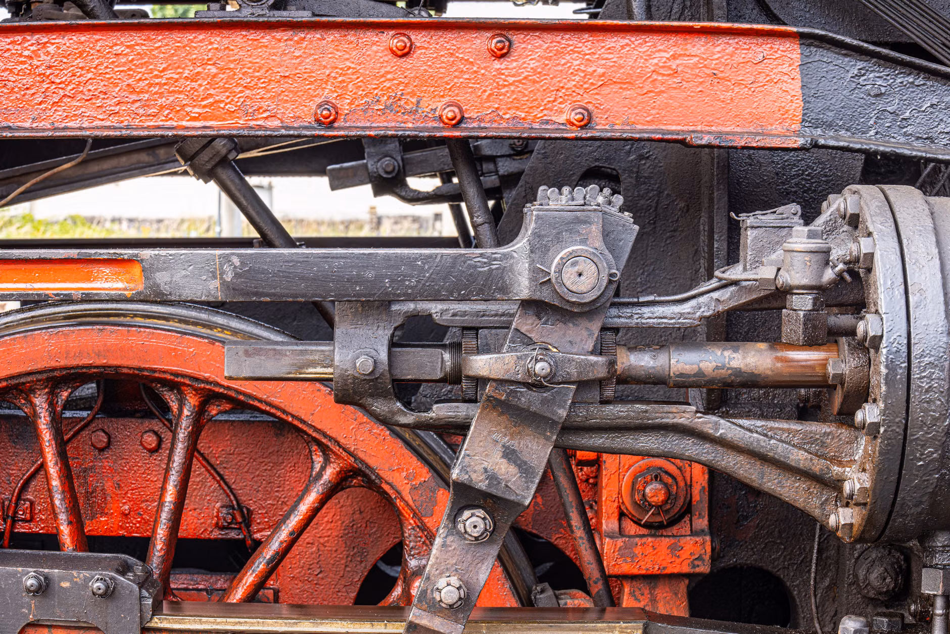 Detailed view of a steam engine wheel with autumn trees in the background.