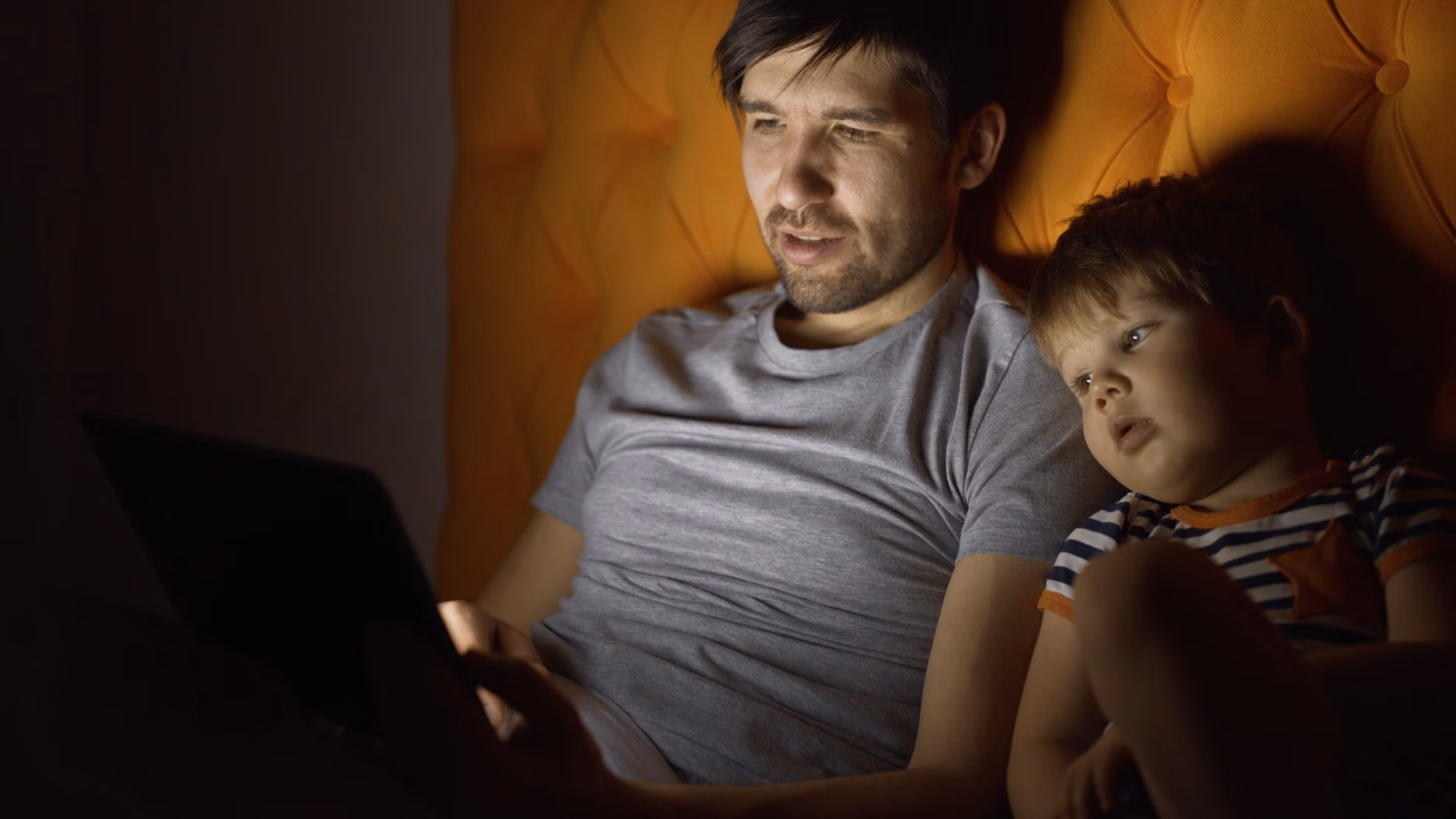 Parent and toddler transitioning from digital screen time to reading a physical book.