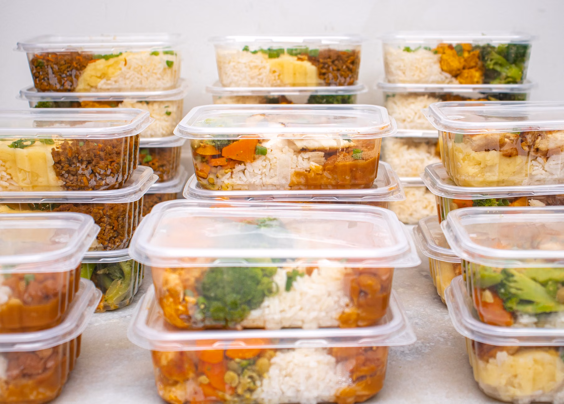 A person organizing a freezer with meal-prepped containers to reduce food waste.