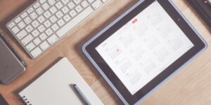 Modern desk setup with digital devices showing a shared scheduling app for co-parenting.