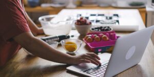 A person reviewing household digital subscriptions on a laptop at a kitchen table.