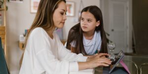 A parent and child discussing financial goals using a tablet in a modern home.