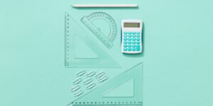 A clean, modern workspace featuring tools for teaching kids financial literacy, including a piggy bank and a savings chart.
