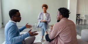 A parent mediating a sibling conflict in a calm living room setting.