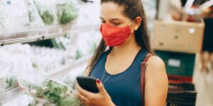 A shopper using a smartphone to check product transparency in a retail store.