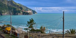 A scenic coastal train traveling along a cliffside overlooking the ocean.