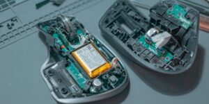 A disassembled wireless mouse on a desk with repair tools