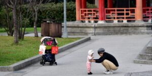 A parent and child exploring nature in an urban park while learning about plant identification.