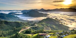 A scenic train winding through a mountain valley during sunset.