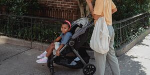 A parent navigating an urban environment with a stroller and bike.