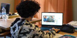 A teenager studying financial concepts on a laptop at home.