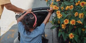 A parent navigating a city environment with a stroller and bike-share options nearby.