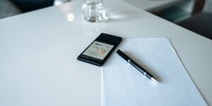 A clean, modern workspace with a smartphone displaying financial data, representing automated budget tracking.