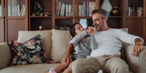 A parent and child sitting together on a sofa, peacefully engaging with a tablet.