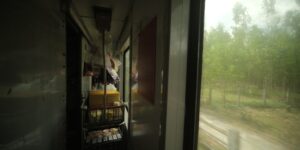 A scenic view of a coastal railway line from inside a modern train carriage.