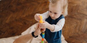 A toddler focused on building a wooden block tower in a bright, modern living room.