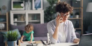 A parent working remotely from a home office, symbolizing the balance of career and family life.