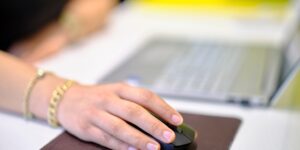 A person repairing a wireless mouse at a desk with precision tools.