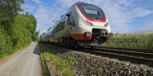 A scenic view of a modern train moving through the countryside.