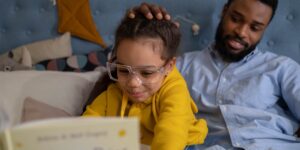A parent and child exploring a book about emotions together in a sunlit room.