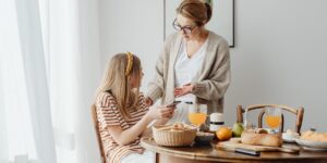 A parent and teenager discussing financial goals at a kitchen table.