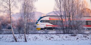 A family enjoying a scenic winter train journey through snowy mountains.