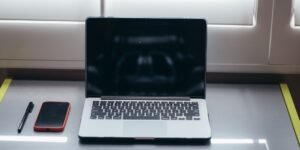 A clean, organized digital workspace with a laptop and smartphone for photo management.
