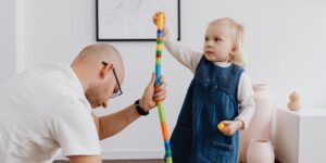 A parent and child engaged in calm, focused play together in a bright living room.