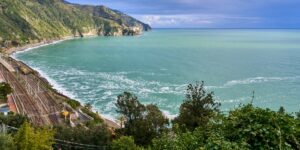 A modern train traveling along a beautiful coastline, representing the future of slow-transit rail travel.