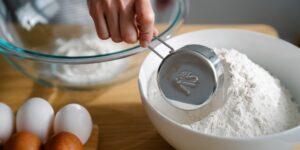 A pre-teen focused on measuring ingredients for a cooking project.