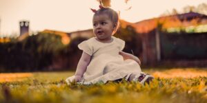 A toddler sitting peacefully in a sunlit park representing nature-based stress recovery.