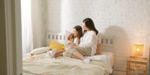 A parent and child reading together in a sunlit, minimalist living room.