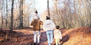 A family of four walking slowly on a forest trail.