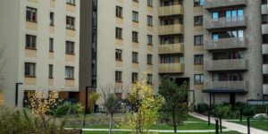 A modern apartment complex with a vibrant public park in the foreground.