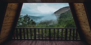 A serene mountain cabin balcony overlooking a misty forest at dawn.