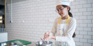 A young person engaged in structured cooking in a bright, modern kitchen.