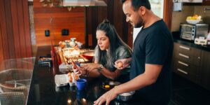 A couple planning a local staycation trip at a kitchen table.