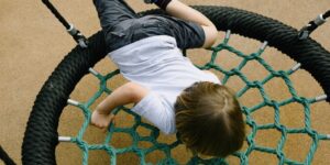 A modular outdoor climbing set in a sunny backyard, representing adaptive play equipment.