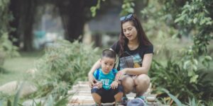 A calm parent and toddler sitting together in a park setting.